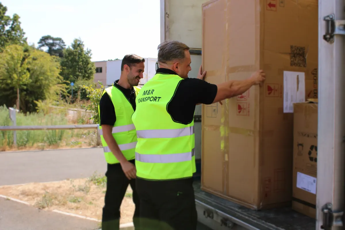 Crew loading a large boxed item at the van tailgate